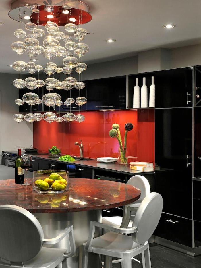 agencement cuisine, plafond blanc avec lustre guirlande en petites lampes suspendues, cuisine avec meubles noirs et crédence rouge