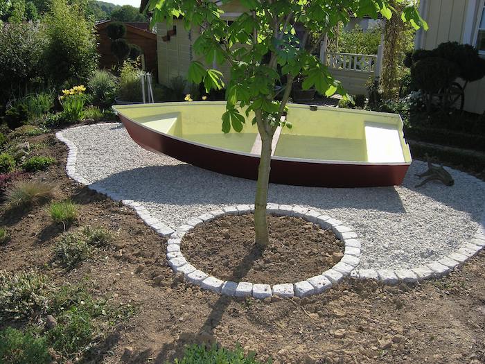 idee deco jardin, technique de jardinage en formes géométriques, petit jardin entouré de pierres avec arbre jeune