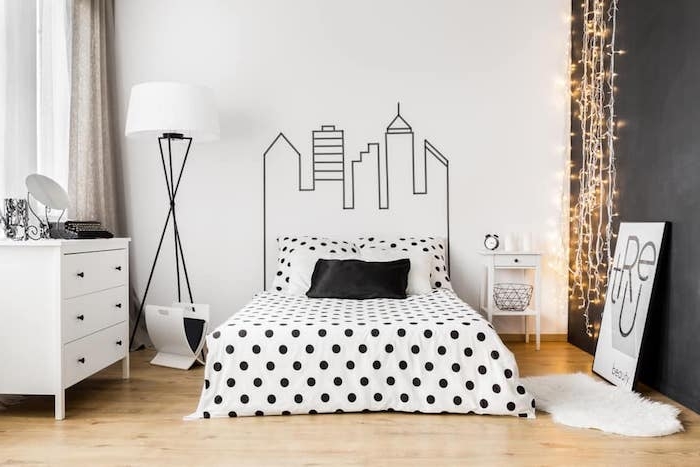 modele de chambre gris et blanc, dessin graphique sur un mur, linge de lit noir et blanc, commode blanche, parquet clair, guirlande lumineuse, tendance hygge