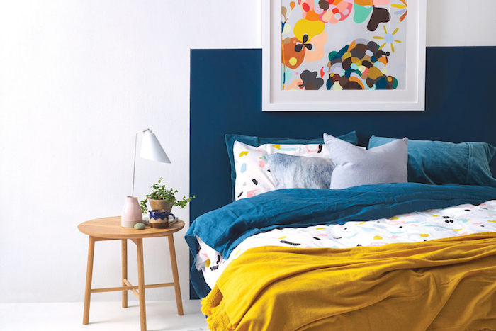 décoration chambre adulte, murs repeint en blanc et tete de lit bleue, table de nuit bois, linge couleur bleue, jaune et blanc, deco cadre peinture abstraite