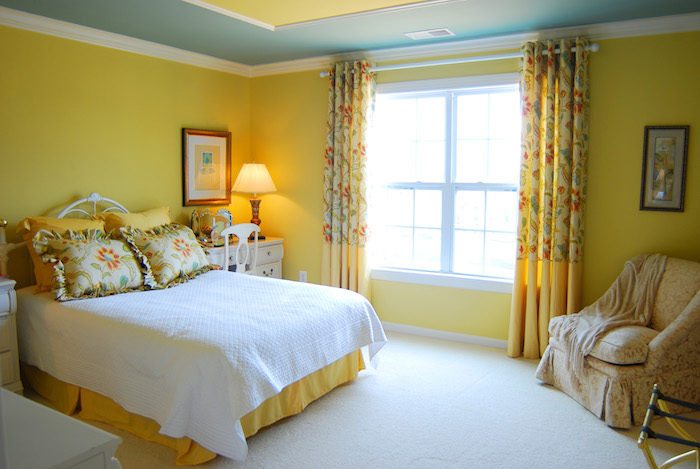 idée comment décorer sa chambre en jaune, motifs florauc sur les rideaux et les coussins lit, tapis blanc, commode blanche