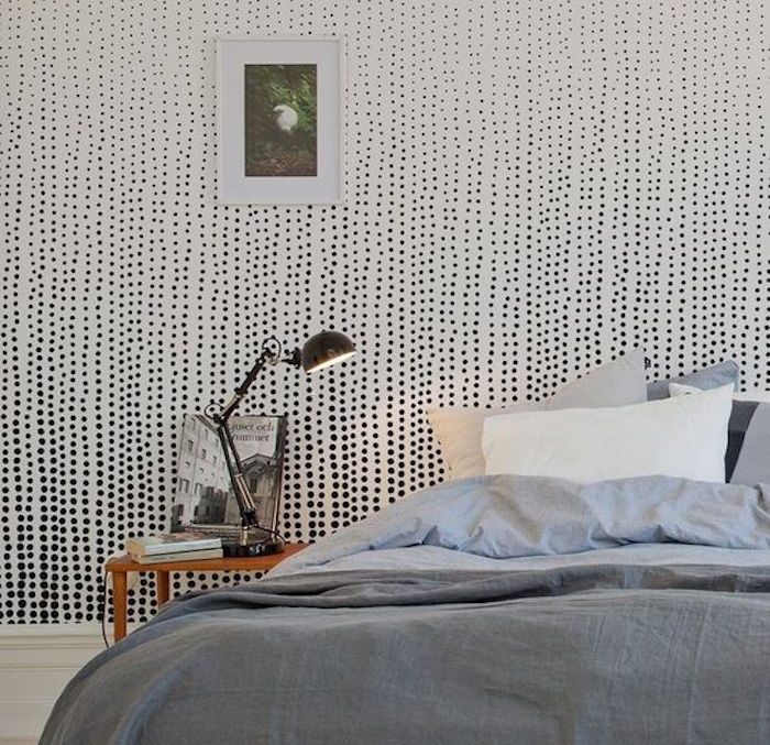 exemple de papier peint scandinave intéressant, mur blanc décoré à pois noirs, linge de lit blanc et gris, table de nuit bois