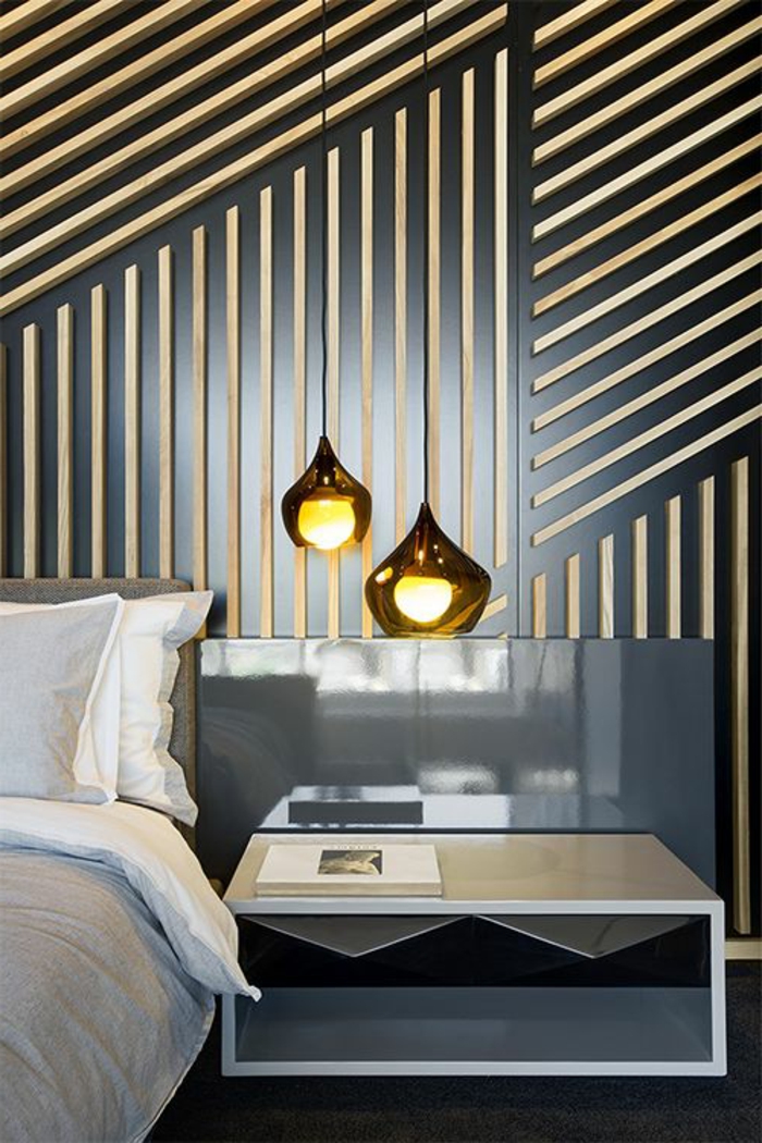 décoration chambre adute avec mur en noir décoré de motifs graphiques en bois clair avec meuble lit bas aux tiroirs noirs