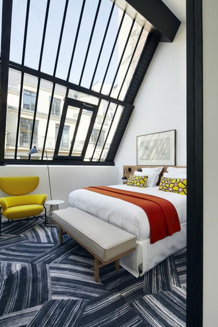 décoration chambre avec plafond en pente et grandes fenetres fauteuil jaune soleil tapis motifs graphiques en bleu et blanc