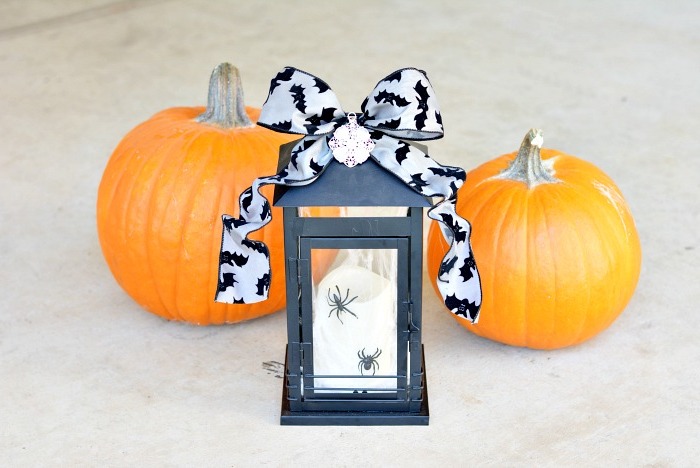 lanterne noir avec ruban noir et blanc et araignées artificielles, citrouilles orange, activité manuelle halloween facile
