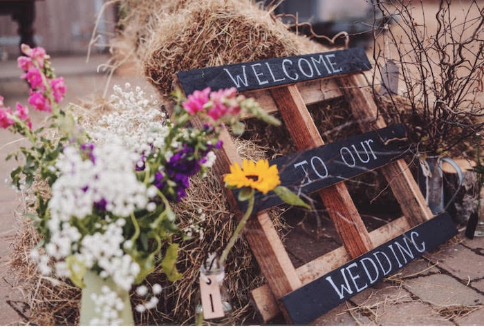 deco mariage a faire soi meme, palette en bois avec texte bienvenue pour accueillir les invités, bouquet de fleurs champetres, botte de paille