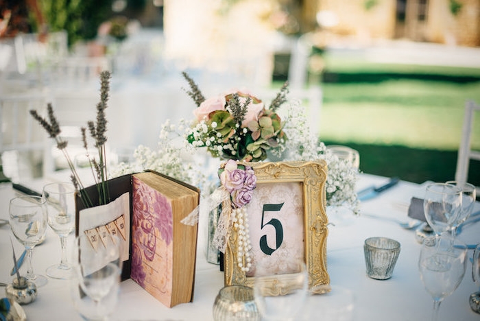 deco mariage vintage champetre, table décoré de cadre vintage, fleurs, collier de perle, bouquin vintage, lavande