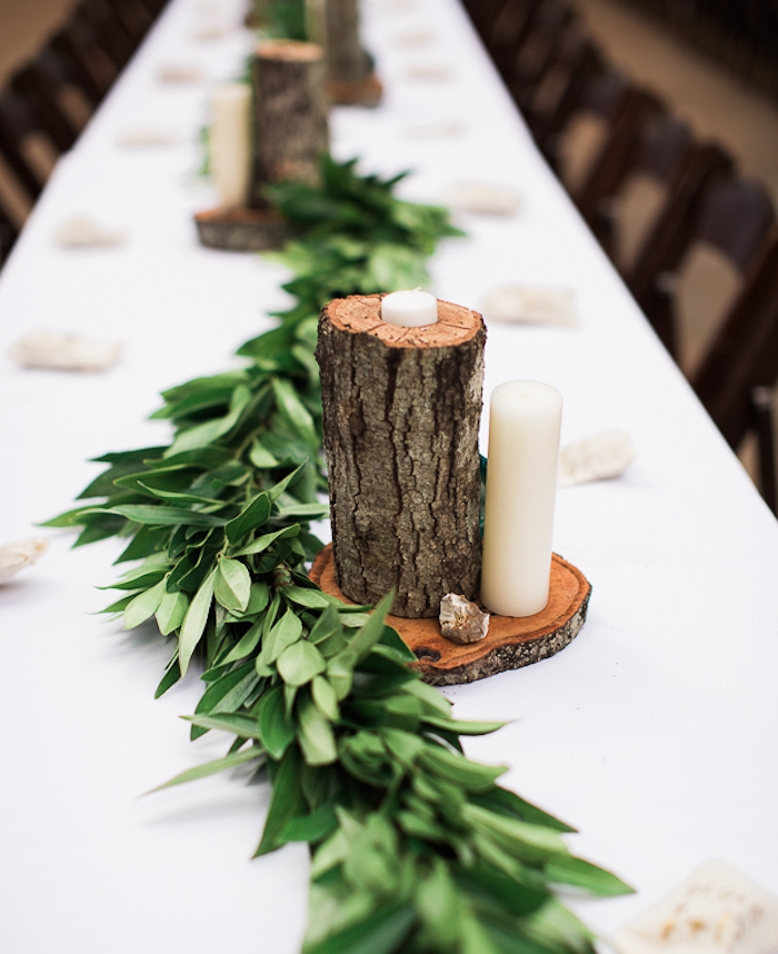 deco table mariage, buches de bois avec des trous pour insérer une bougie, bougies blancs sur une rondelle en bois, guirlande verte fleuri