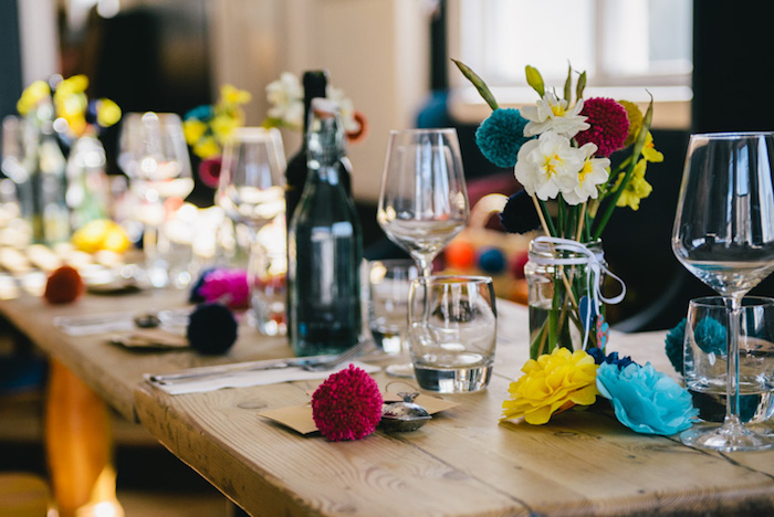 decoration table mariage en bois brut style campagne chic, pompons colorés, fleurs en tissu, pots en verre avec des fleurs dedans