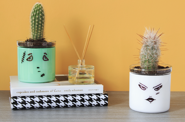 bricolage halloween avec des pots en verre repeints a l interieur et des dessins visage traits noirs a l exteireur, cactus