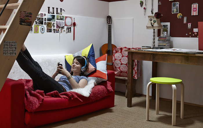 chambre ado fille, canapé rouge couvert de plaid moelleux rouge, murs blancs décorés de cadres photos