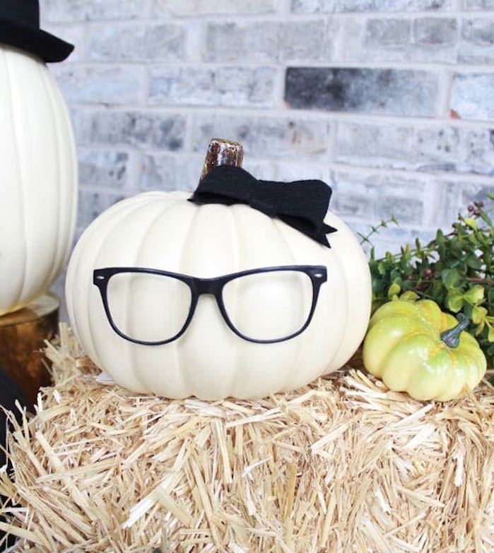 décoration halloween a fabriquer,. une citrouille au noeud noir et des lunettes sur une botte de paille