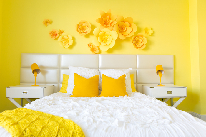 couleur chambre adulte jaune, linge de lit blanc et jaune, deco murale de fleurs en papier, table de nuit blacnhe