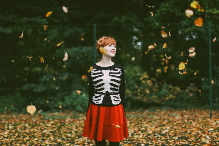 pull avec motif squelette, jupe rouge, collants noirs, coiffure chignon tressé, paysage automnal, déguisement halloween femme