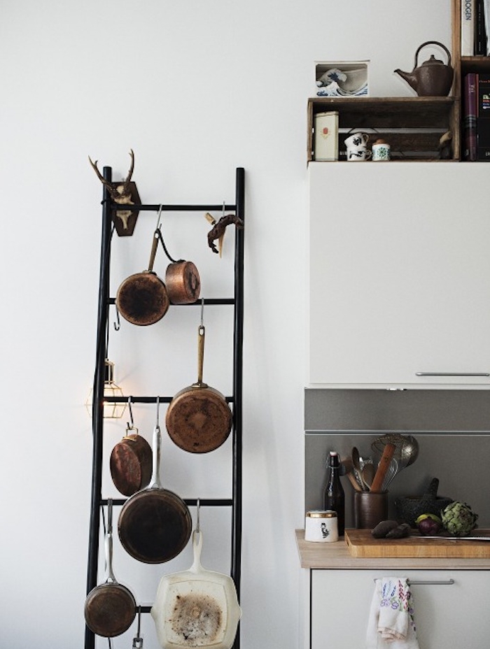 echelle decorative en metal noir pour la cuisine, ustensiles de cuisine, plan de travail bois, façade cuisine blanche