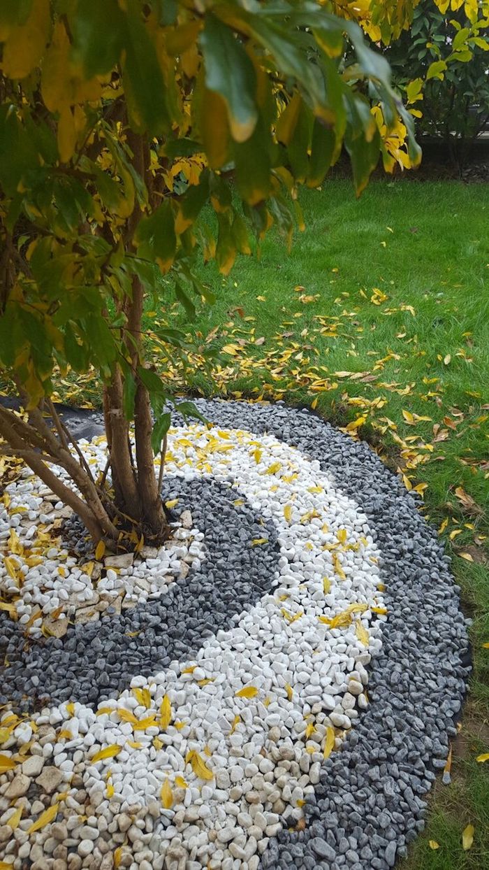 parterre de fleurs, gazon vert couvert de feuilles orange et jaunes, déco jardinage en cailloux blancs et noirs 