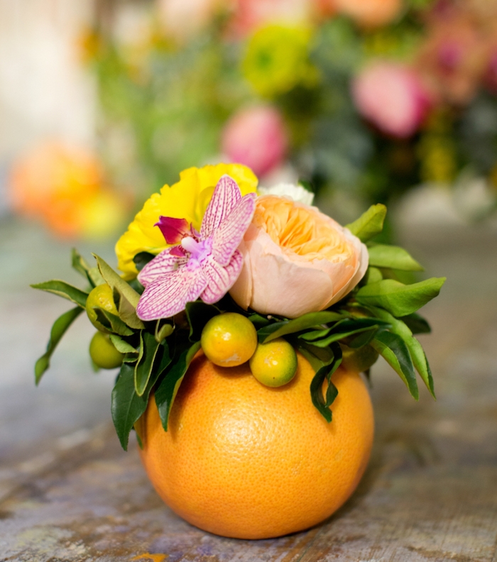 diy mariage tropical, un orange creusé avec un petit bouquet de fleurs dedans, deco simple centre de table mariage