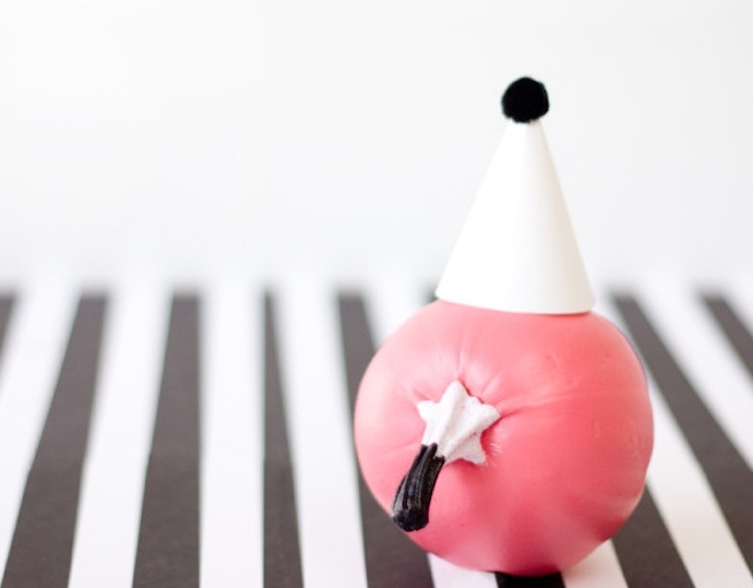 idée comment décorer une citrouille, repeinte en rose avec chapeau d anniversaire blanc et pompon noir, activite manuelle facile