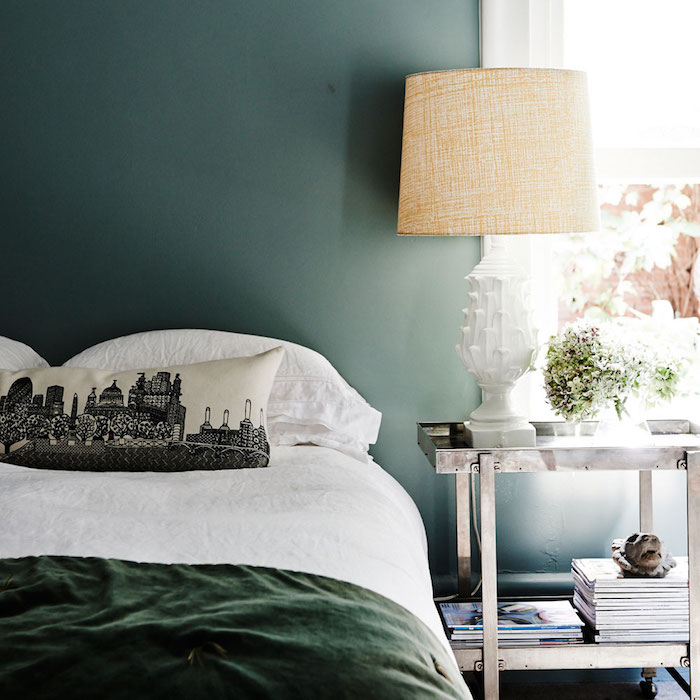 couleur chambre adulte, vert foncé, linge de lit blanc et vert, coussins avec imprimé paysage urbain, etagere metallique design