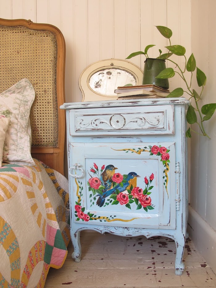 idée comment renover un meuble, table de nuit repeinte en bleu pastel avec dessin oiseaux et motifs floraux, parquet blanchi, lit vintage, plante verte