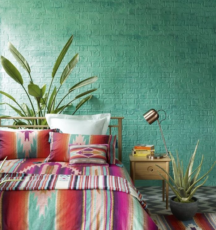 couleur chambre adulte, mur en briques repeint en vert, linge de lit boheme chic à motifs colorés, revetement sol gris et blanc, lampe design, plantes vertes