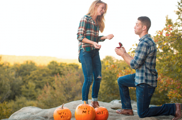 idée surprise mariage en automne, les mots veux tu m epouser gravés sur des citrouilles orange, proposition sur une petite colline dans la forêt