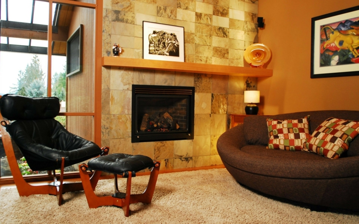 idee deco salon cocooning, chaise noire en cuir avec un taboret, papier peint pierre apparente, canapé marron, tapis beige