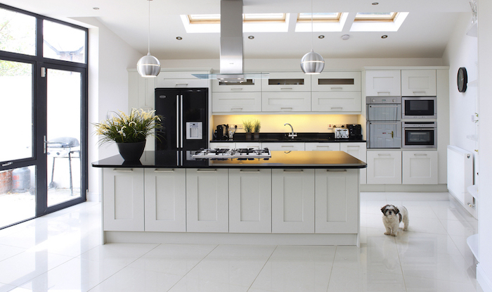 cuisine avec ilot central, fenêtres de plafond et éclairage suspendu, meubles de cuisine en blanc et noir