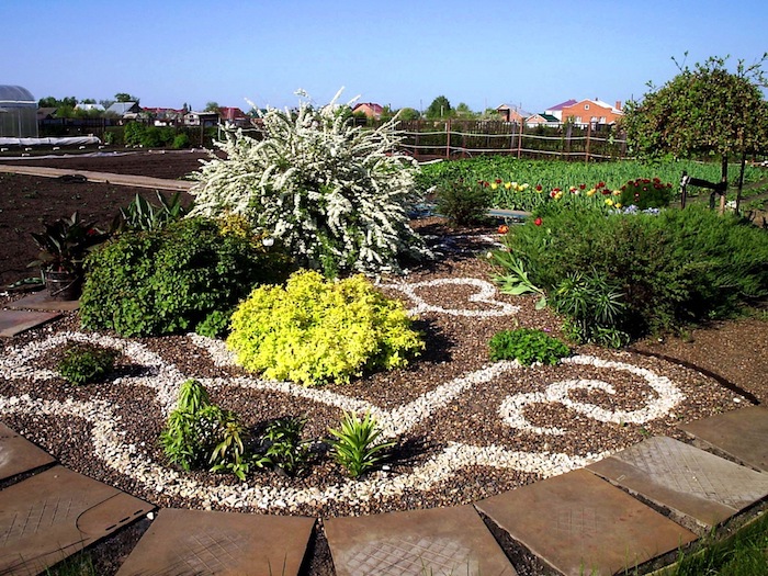 parterre de fleurs, art de jardinage avec dessin en terre et cailloux, décoration de jardin formes volutes