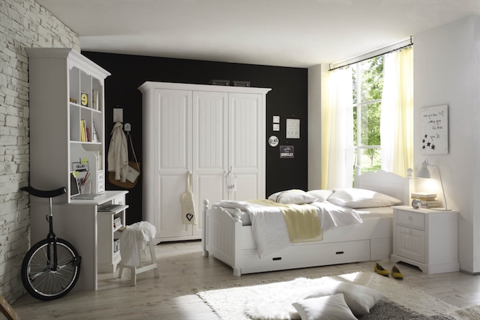 chambre à coucher aux murs blancs et noirs, tapis moelleux en blanc avec coussins décoratifs