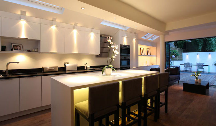 cuisine avec ilot central, meubles de cuisine blanc sans poignées et avec comptoir noir, aménagement de cuisine en longueur