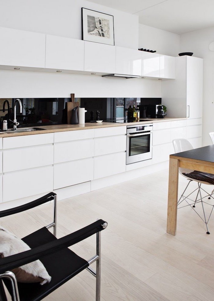 meuble bas cuisine en blanc sans poignées, cuisine en blanc avec crédence noire, revêtement de sol en bois clair