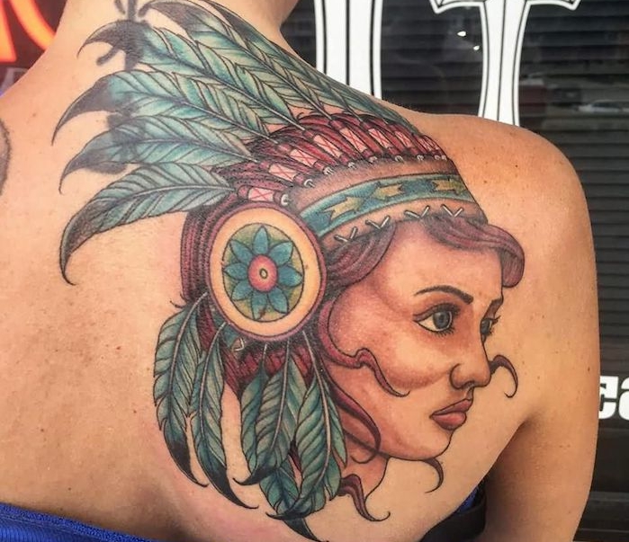 tatouage indien d amérique, art corporel sur dos féminin avec visage femme aux cheveux rouges et plumes bleus