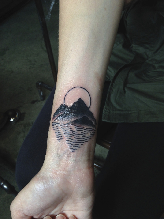 un tatouage paysage graphique et géométrique représentant la mer, l'océan et le soleil