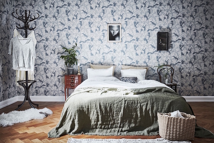 papier peint vintage, motifs bleus sur un fond blanc, parquet clair, linge de lit blanc, couverture verte, porte manteau retro