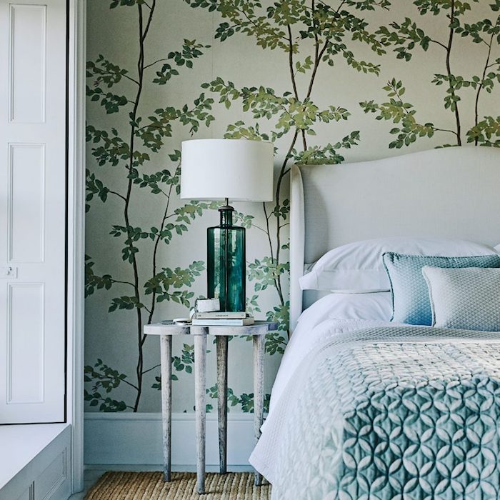 papier peint chambre adulte, greenery, lit blanc, couverture bleu-vert, tapis marron, table de nuit bois, lampe sur pied originale
