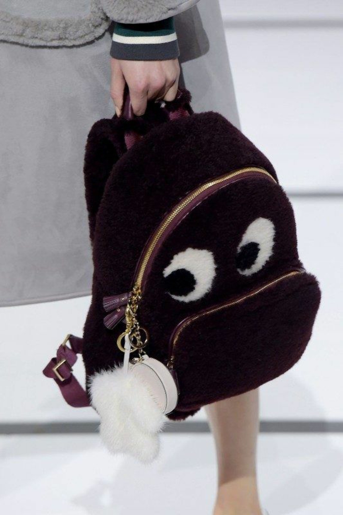 sac à dos femme tendance en peluche couleur prune avec des yeux et avec un grand pouf décoratif en blanc 