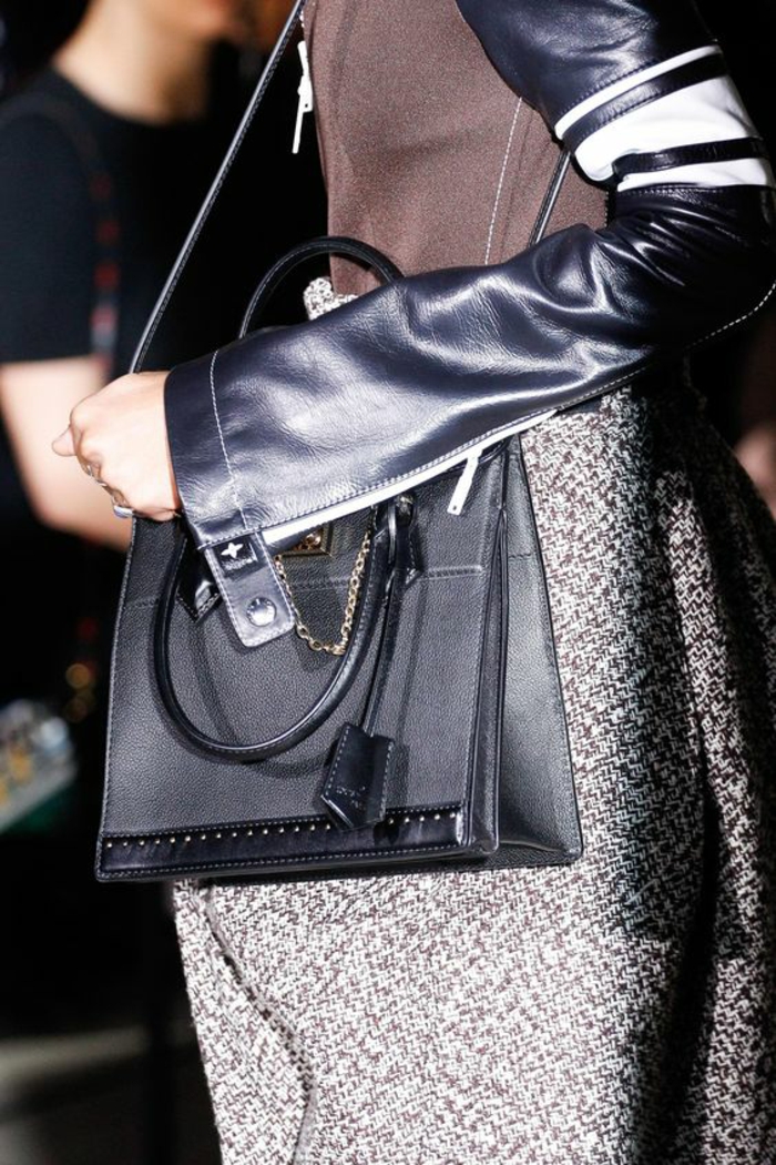sac a dos vintage en noir en forme rectangulaire avec logo et petite chainette décorative en métal couleur argent création de Louis Vuitton