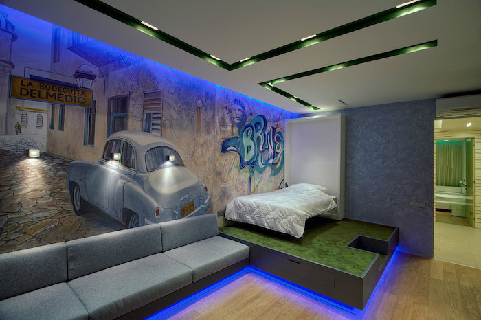 chambre ado garçon, canapé en tissu gris et lit en bois, éclairage néon bleu sol et plafond, plafond suspendu en blanc