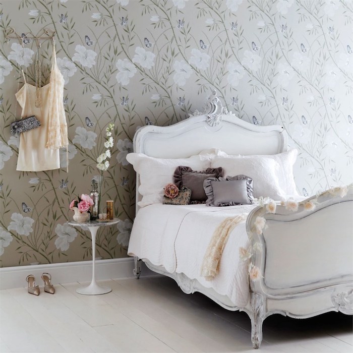 papier peint vintage et lit baroque dans une chambre design feminine, coussins gris sur un linge blanc, parquet blanchi, revetement mur motifs floraux sur un fond gris