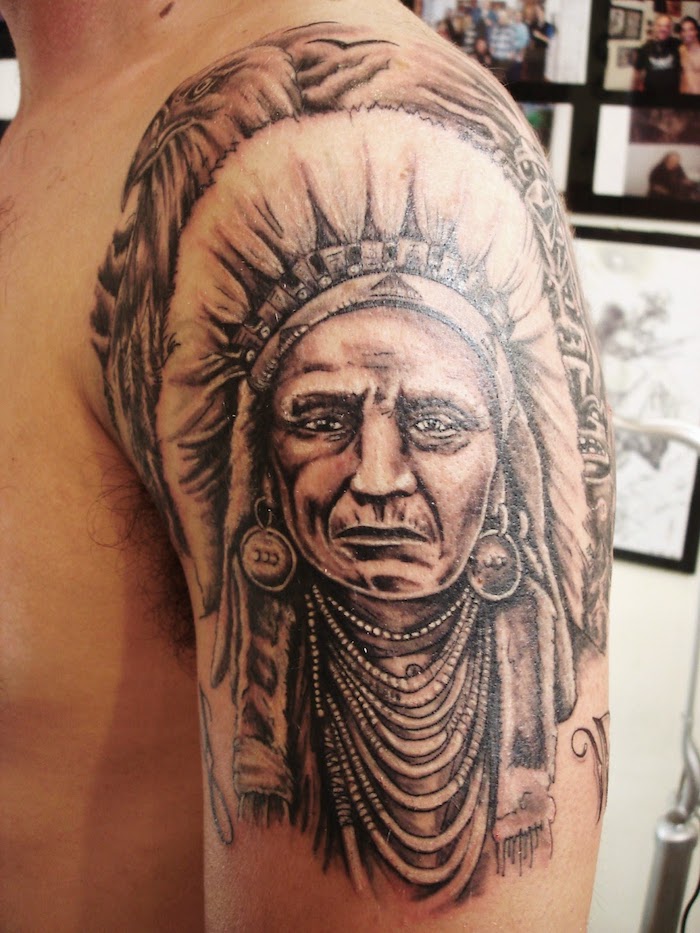 motif amérindien, tatouage sur bras et épaule pour homme, dessin en encre tête autochtone avec plumes