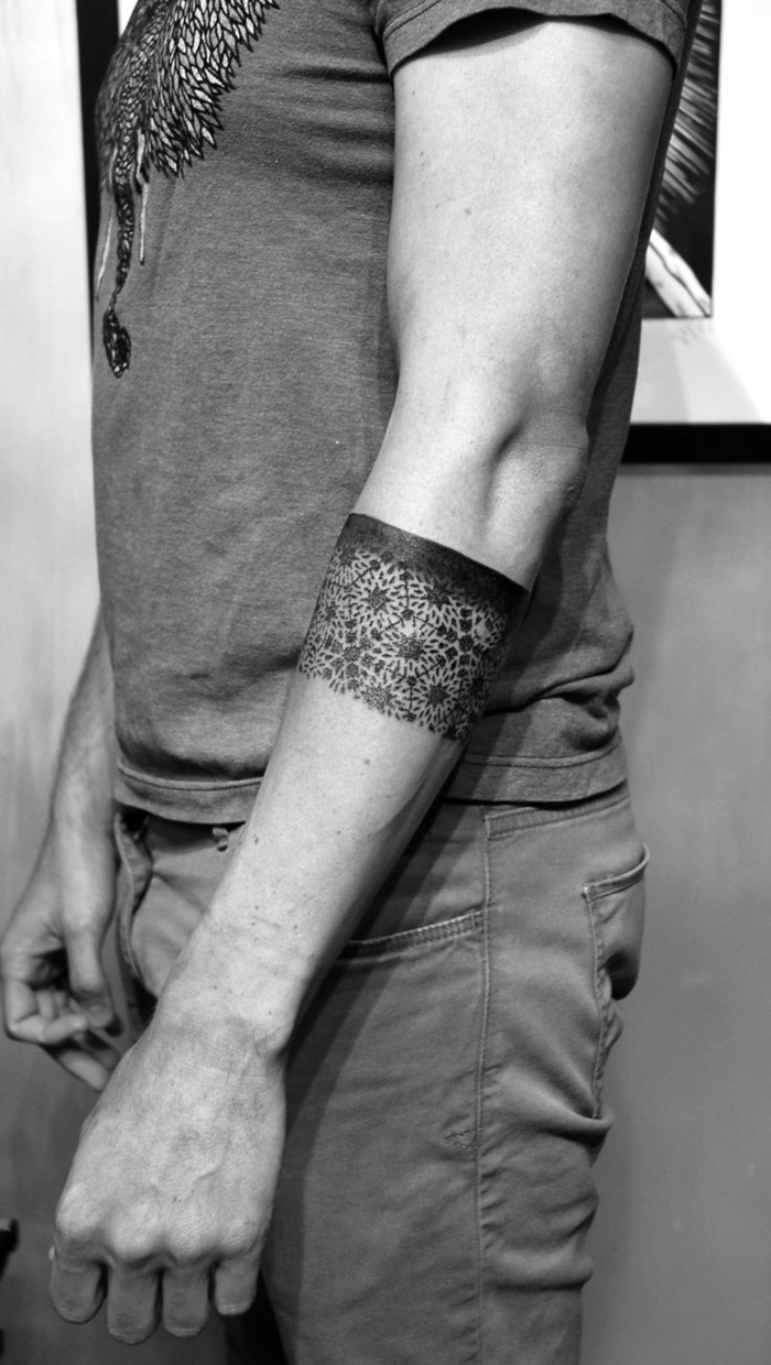 un tatouage geometrique brassard au design original qui joue sur le contraste entre la bande noire et les motifs rosace 