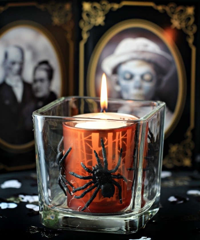 bougie dans un petit verre avec es araignées artificielles et fond de photographies en noir et blanc effrayants dans des cadres baroques