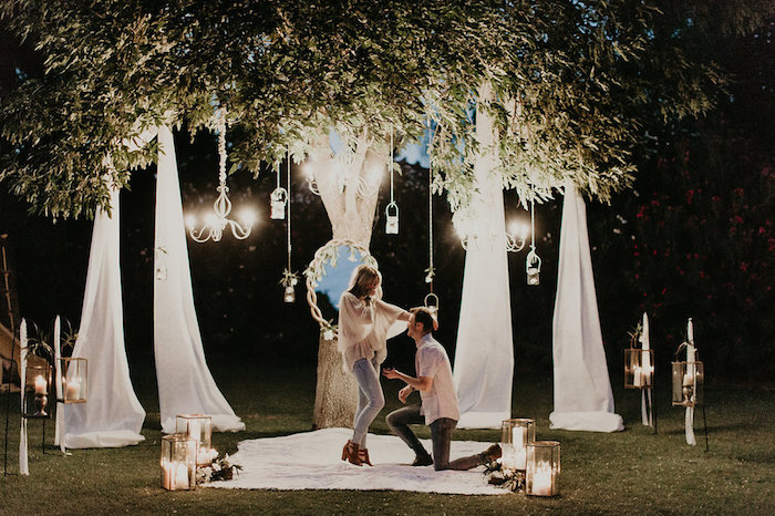 idée de demande en mariage romantique sur un pré dans la forêt, décoration de miroir, voiles blanches, lanternes avec bougies, lustres élégantes
