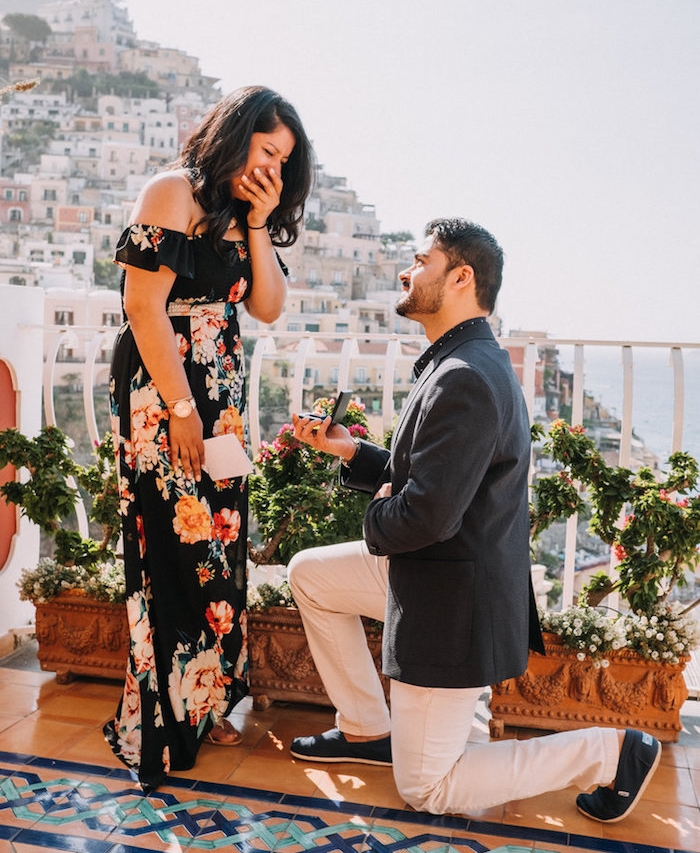 demande en mariage originale pendant des vacances en italie, vue panoramique sur une ville, terrasse italienne, femme en robe fleurie, homme en costume
