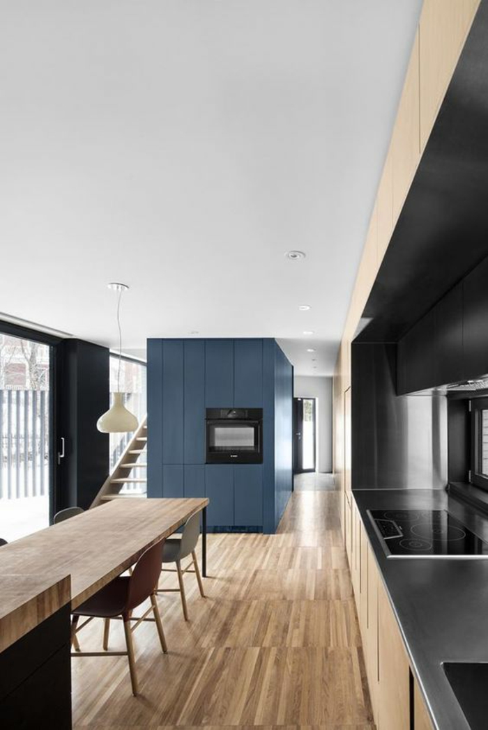 cuisine bleu, peinture bleu canard, salle à manger meublée en longueur, parquet aux nuances du beige et du marron, zone des fourneaux et du lavabo en noir