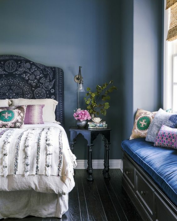 deco chambre adulte bleu avec grand lit au dossier en style hindou et banc de rangement avec des coussins bleu royal et des coussinets colorés