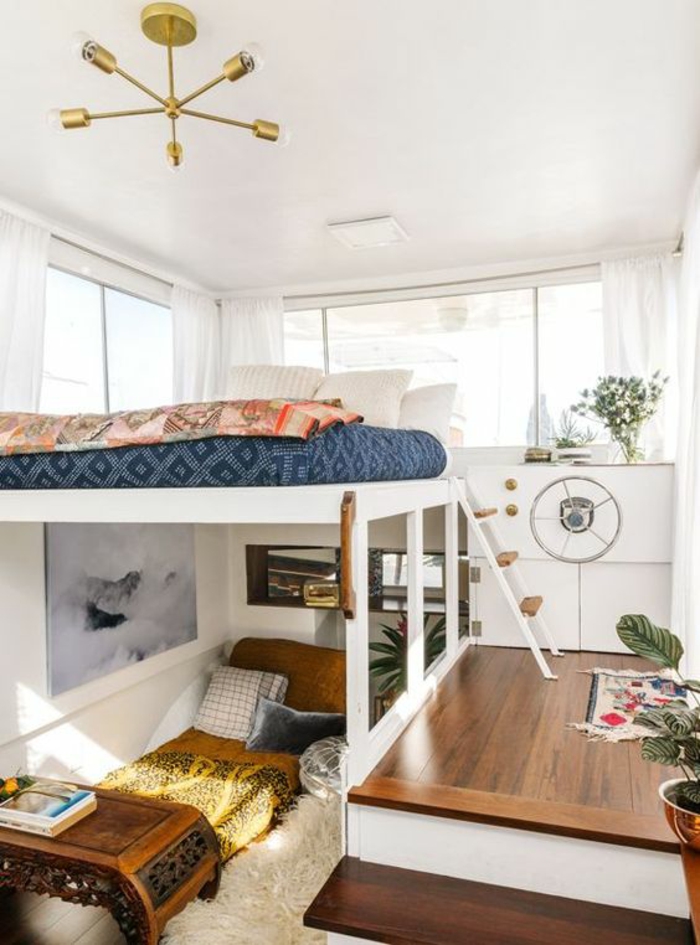 chambre de 9m2 sur un yacht, avec deux lits superposés, luminaire en couleur or, plafond blanc finition lisse, avec des plantes vertes 