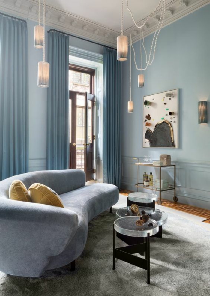 couleur bleu gris dans un salon au plafond haut avec canapé en bleu gris et plafond aux frises blanches et cinq luminaires suspendus décor artistique