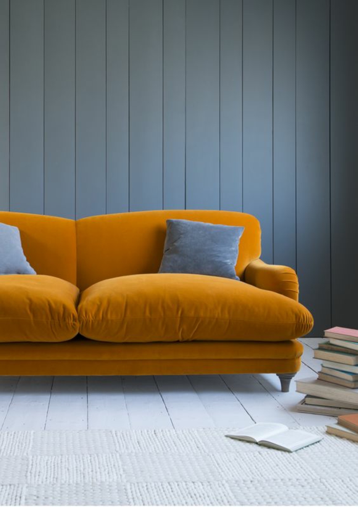 azur couleur bleu gris sur un mur revêtu de bois peint en bleu gris avec grand canapé moelleux en velours orange vitaminé